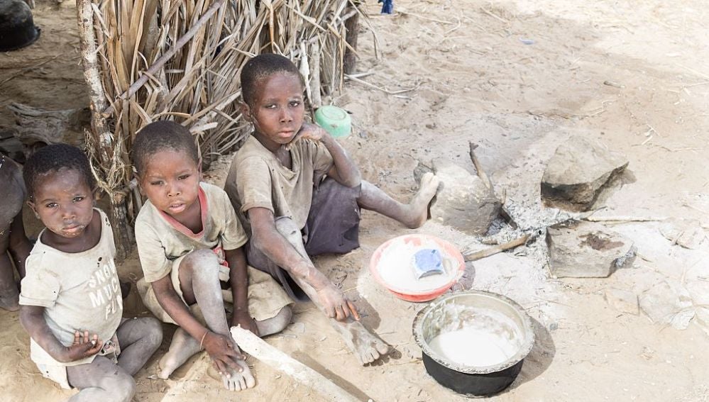 Tres niños esperan al camión que les traerá el agua en África