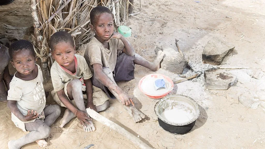 Tres niños esperan al camión que les traerá el agua en África Tres niños esperan al camión que les traerá el agua en África