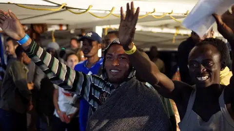 Algunos de los migrantes a bordo del Open Arms momentos antes de desembarcar en Lampedusa Algunos de los migrantes a bordo del Open Arms saludan momentos antes de desembarcar en Lampedusa