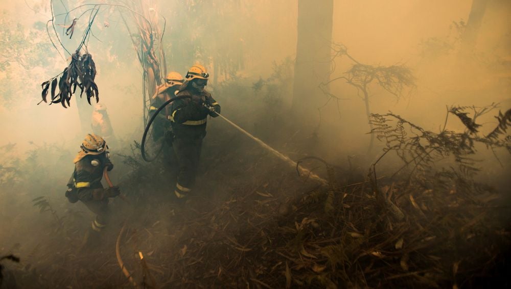 Un grupo de bomberos trabaja en las labores de extinción del incendio forestal declarado este jueves en la localidad coruñesa de Porto do Son