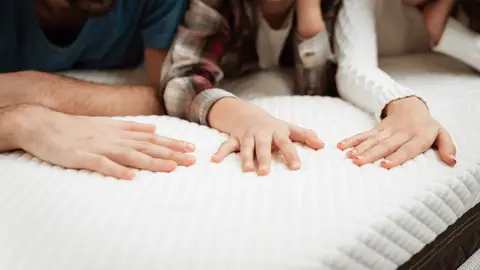 Familia en el colchón de la cama Familia en el colchón de la cama