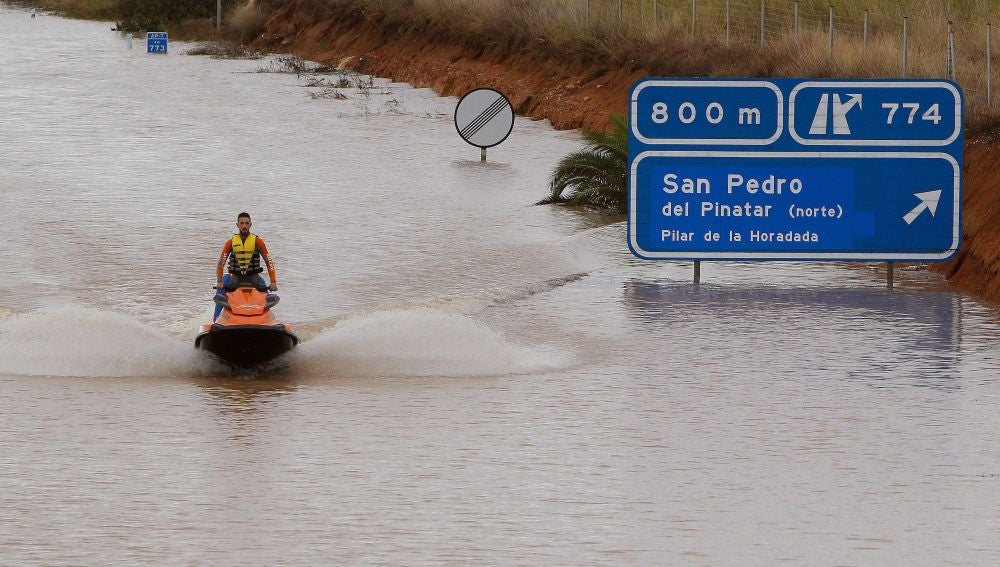 Un miembro de los servicios de rescate cruza en moto acuática la salida del túnel de la AP-7 en Pilar de la Horadada