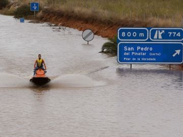 Un miembro de los servicios de rescate cruza en moto acuática la salida del túnel de la AP-7 en Pilar de la Horadada