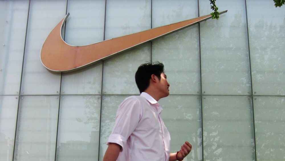 Un hombre pasa junto al letrero de una tienda Nike