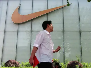 Un hombre pasa junto al letrero de una tienda Nike Un hombre pasa junto al letrero de una tienda Nike