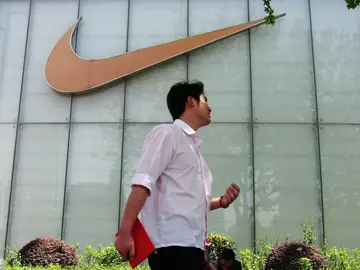 Un hombre pasa junto al letrero de una tienda Nike Un hombre pasa junto al letrero de una tienda Nike