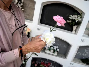 Una mujer lleva flores a un cementerio Una mujer lleva flores a un cementerio