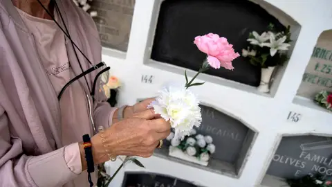 Mujer dejando flores en un cementerio Mujer dejando flores en un cementerio