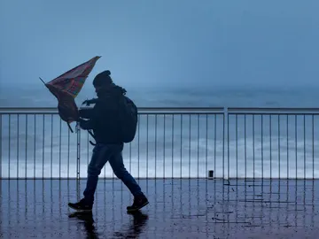 Imagen de archivo: un hombre pasea con un fuerte viento. Imagen de archivo: un hombre pasea con un fuerte viento.