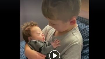 La imagen de un niño cantando a su hermano bebé con Síndrome de Down