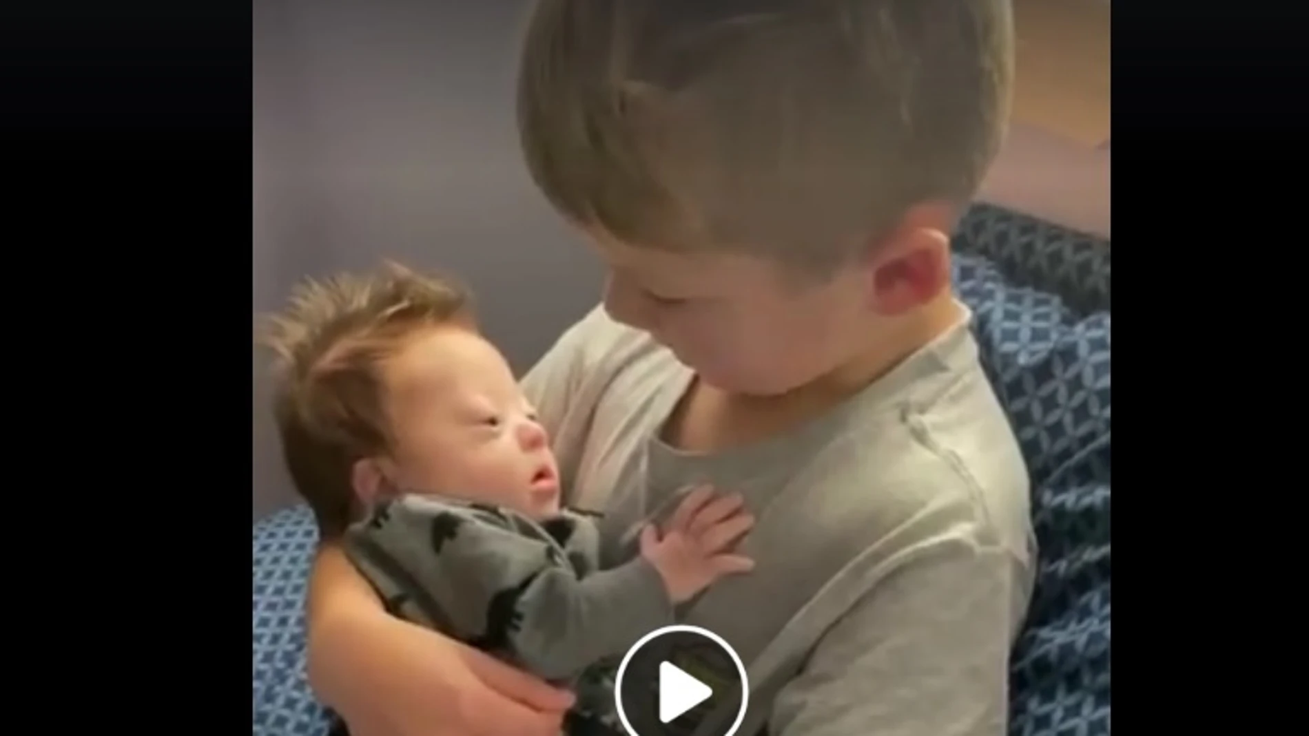 La imagen de un niño cantando a su hermano bebé con Síndrome de Down La imagen de un niño cantando a su hermano bebé con Síndrome de Down