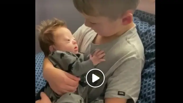 La imagen de un ni&ntilde;o cantando a su hermano beb&eacute; con S&iacute;ndrome de Down