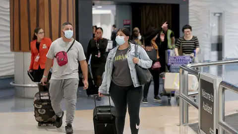 Pasajeros con máscaras en una terminal de aeropuerto Pasajeros con máscaras en una terminal de aeropuerto