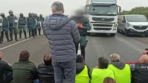 El momento en el que un antidisturbio convence a los agricultores que llevaban dos horas cortando la autovía A4 en ambos sentidos El momento en el que un antidisturbio convence a los agricultores que llevaban dos horas cortando la autovía A4 en ambos sentidos