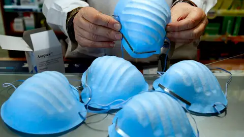 Un hombre manipulando varias mascarillas Un hombre con varias mascarillas