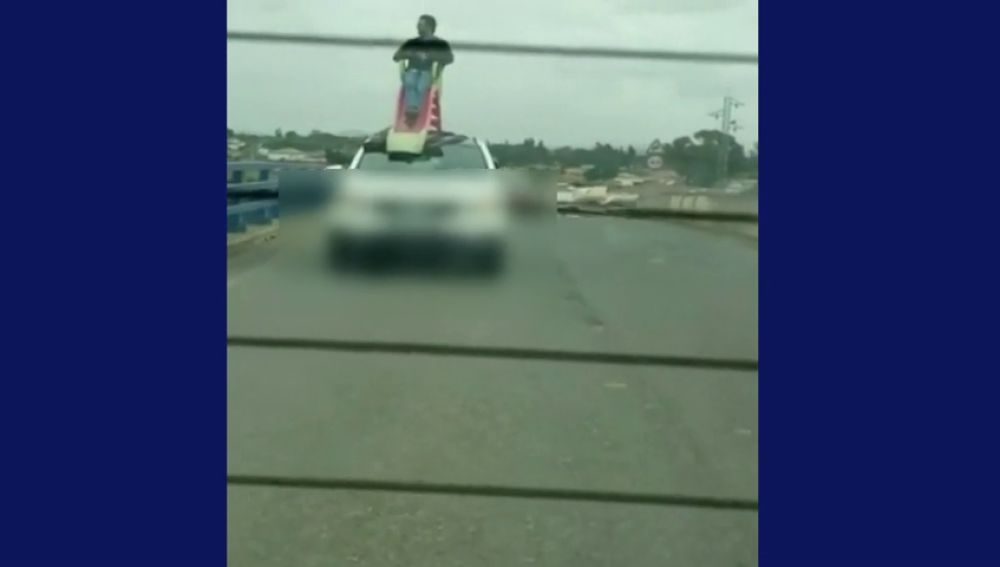 Un conductor circula con otro hombre subido en un tobogán en el techo del coche, ambos han sido detenidos