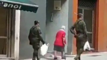 Dos militares ayudan a una anciana a llevar la compra a casa en Gijón durante la cuarentena por coronavirus