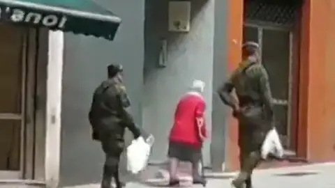 Dos militares ayudan a una anciana a llevar la compra a casa en Gijón durante la cuarentena por coronavirus Dos militares ayudan a una anciana a llevar la compra a casa en Gijón durante la cuarentena por coronavirus