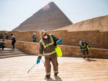 Varias personas desinfectan las inmediaciones de las pirámides de Giza en El Cairo