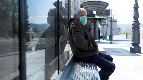 Un hombre con una mascarilla en una parada de autob&uacute;s en Ourense.