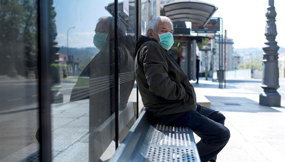 Un hombre con una mascarilla en una parada de autobús en Ourense.