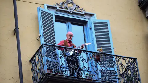Un hombre toca la guitarra en su balcón, en una ciudad italiana Un hombre toca la guitarra en su balcón, en una ciudad italiana