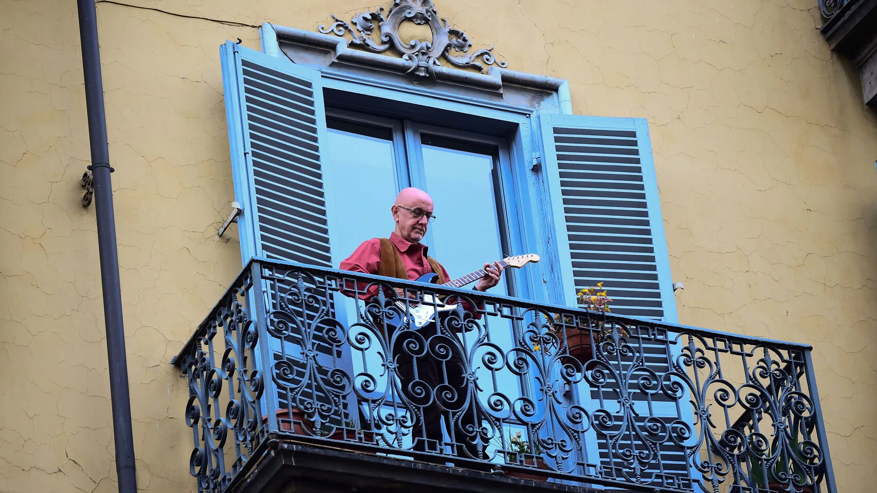 Un hombre toca la guitarra en su balc&oacute;n, en una ciudad italiana
