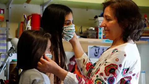 Una mujer prueba mascarillas a dos niñas Una mujer prueba mascarillas a dos niñas