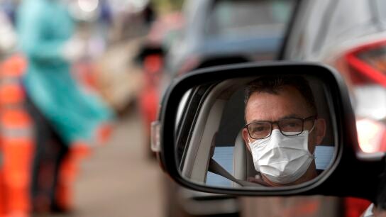 Un hombre con mascarilla en su coche