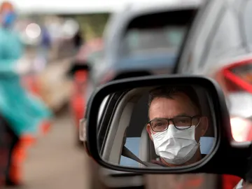 Un hombre con mascarilla en su coche Un hombre con mascarilla en su coche