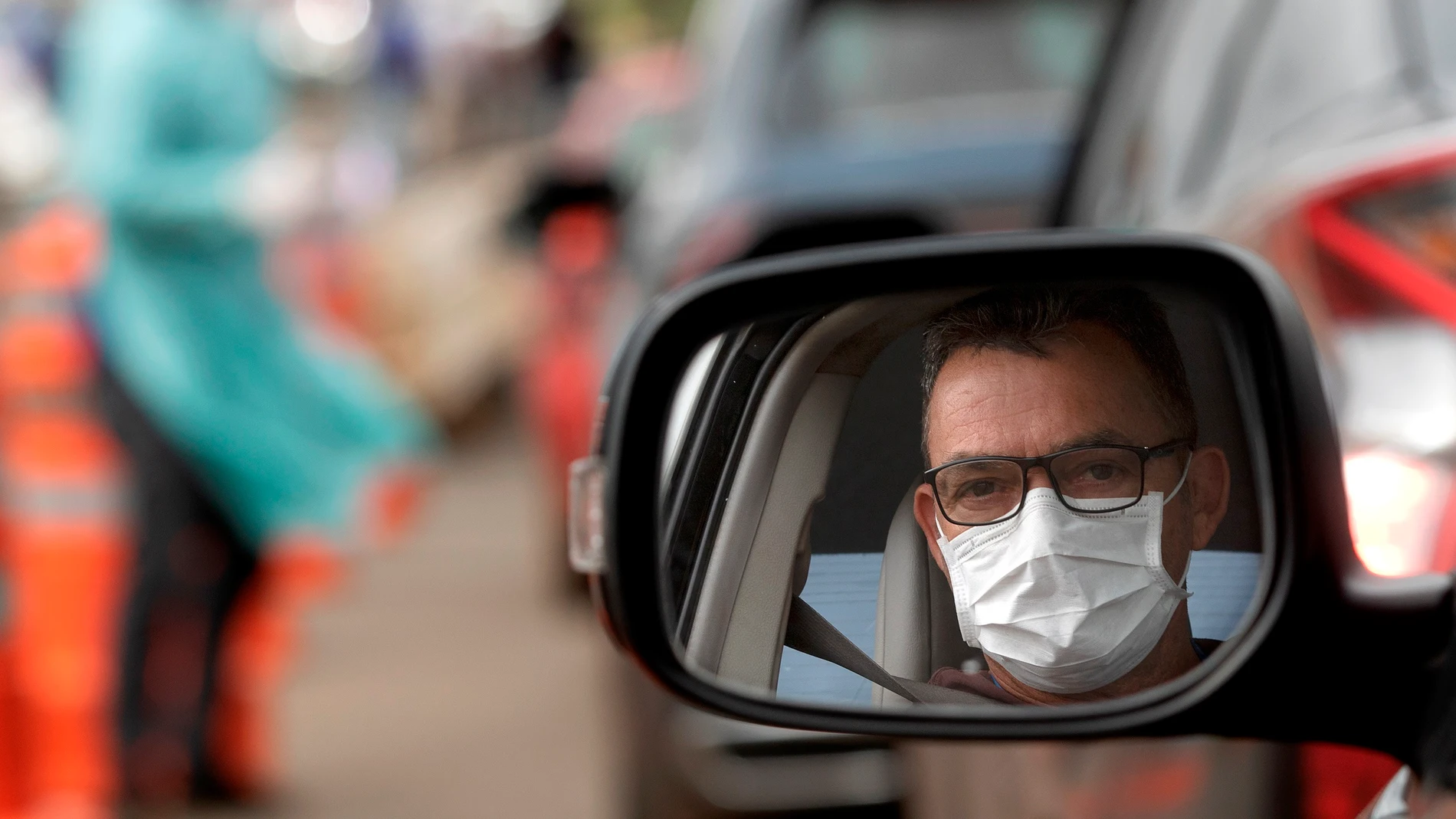 Un hombre con mascarilla en su coche Un hombre con mascarilla en su coche