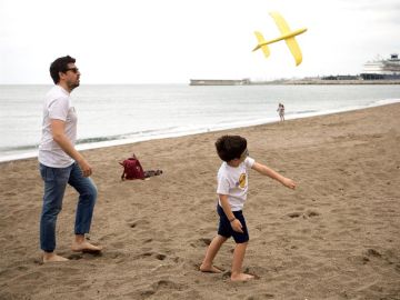 Un niño juega con su padre en la playa de la Malagueta tras 43 días de confinamiento