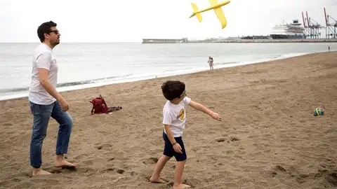 Un niño juega con su padre en la playa de la Malagueta tras 43 días de confinamiento Un niño juega con su padre en la playa de la Malagueta tras 43 días de confinamiento