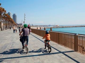 Una familia circula en bici por el paseo marítimo de Barcelona
