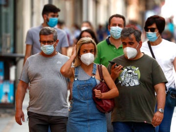 Ciudadanos pasean por la calle protegidos con mascarillas