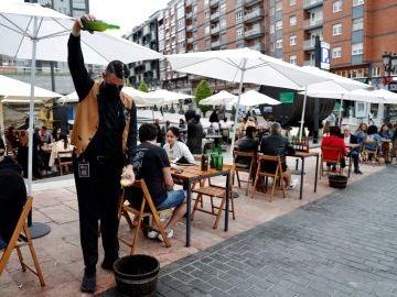 Un camarero escancia sidra en una terraza de Asturias