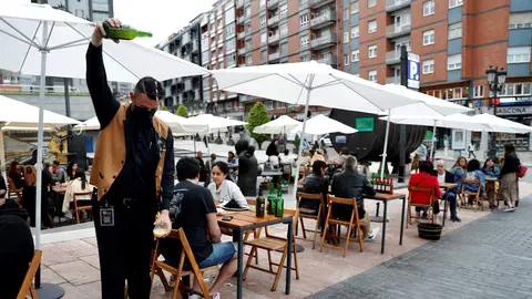 Un camarero escancia sidra en una terraza de Asturias Un camarero escancia sidra en una terraza de Asturias
