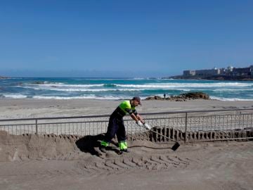 Un operario del concello de A Coruña trabaja en el acondicionando la playa de Riazor