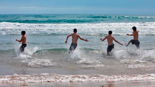  Varios j&oacute;venes disfrutan del mar en la playa de Gand&iacute;a