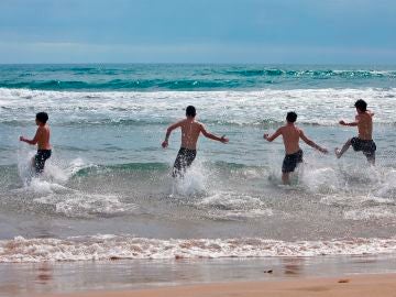  Varios jóvenes disfrutan del mar en la playa de Gandía