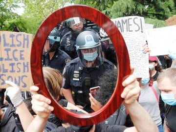 Un oficial de policía de Nueva York reflejado en el espejo de un manifestante