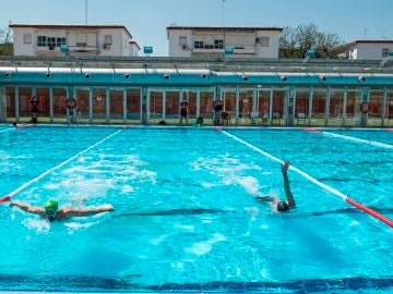 Dos personas nadan en la piscina municipal del barrio sevillano de Tiro de Linea
