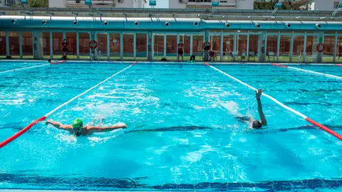 Dos personas nadan en la piscina municipal del barrio sevillano de Tiro de Linea Dos personas nadan en la piscina municipal del barrio sevillano de Tiro de Linea