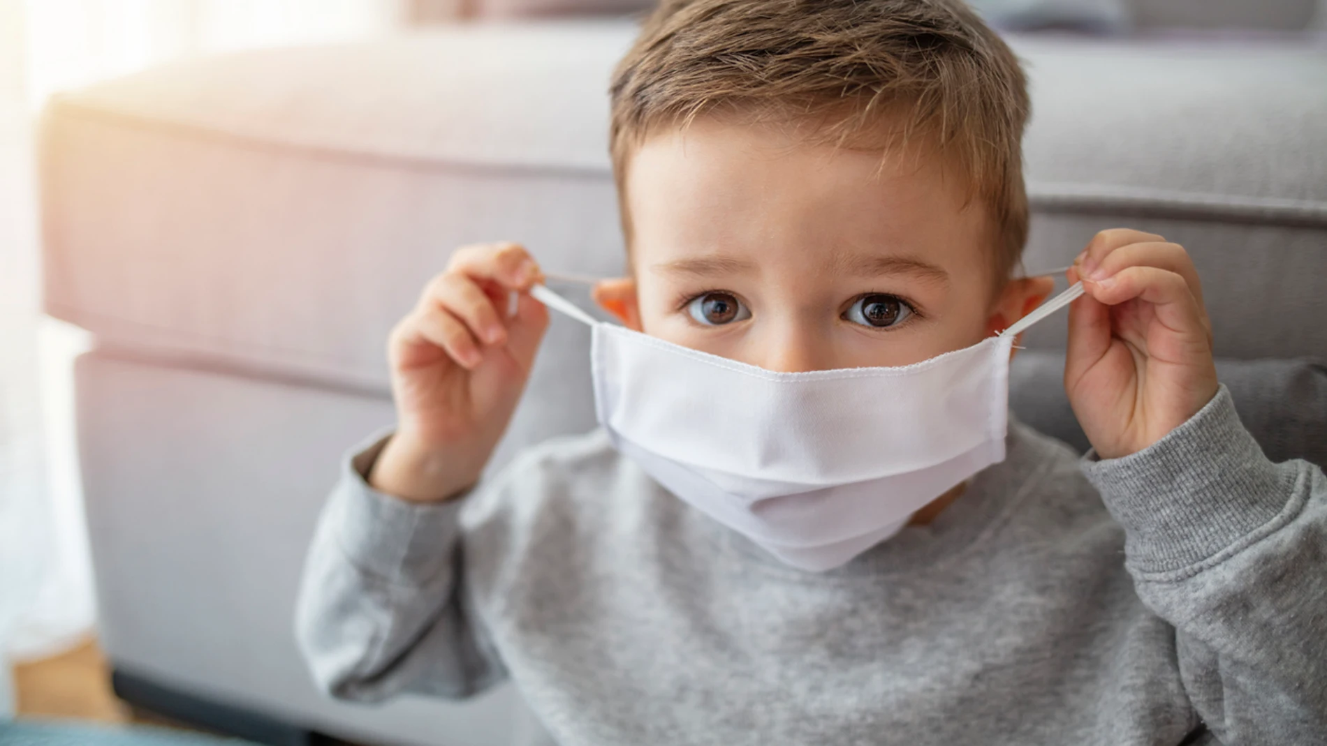 Niño poniéndose mascarilla Niño poniéndose mascarilla