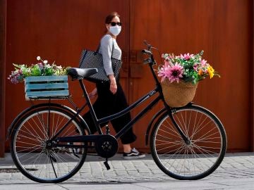 Una mujer con mascarilla pasa junto a una bicicleta aparcada en una calle de Ávila