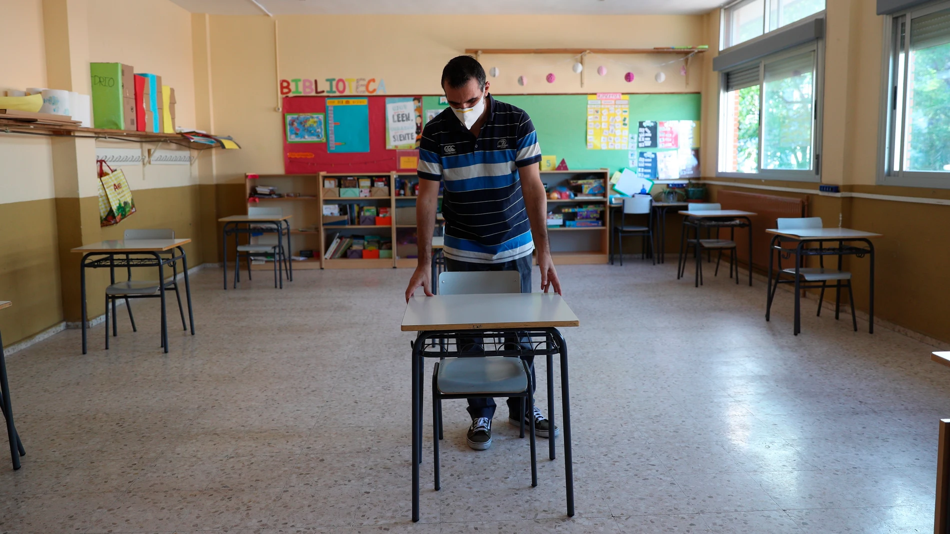 Un profesor coloca las mesas para mantener la distancia de seguridad Un profesor coloca las mesas para mantener la distancia de seguridad