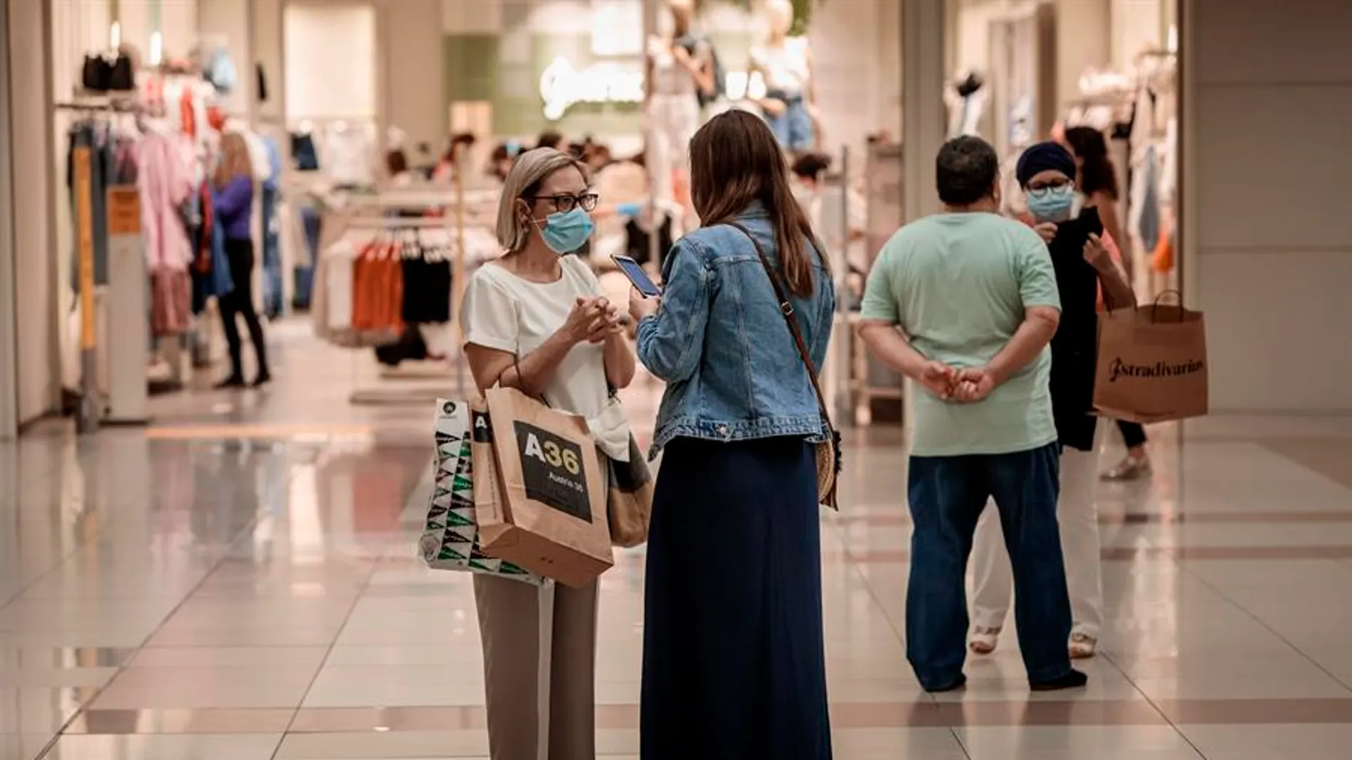 Personas con mascarilla compran en un centro comercial Personas con mascarilla compran en un centro comercial