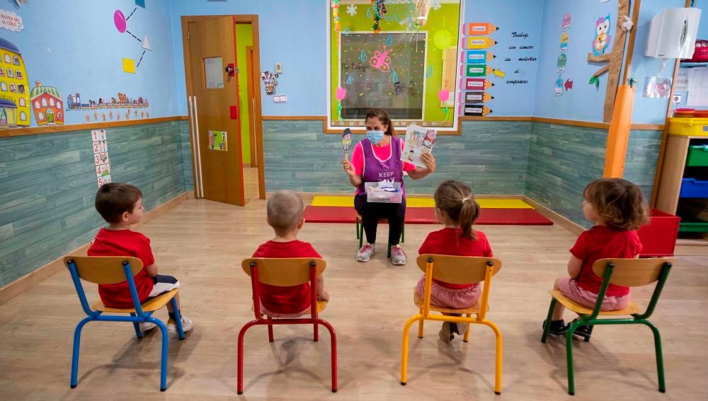 Una educadora de un centro de educación infantil les cuenta un cuento a varios niños y niñas en Murcia 