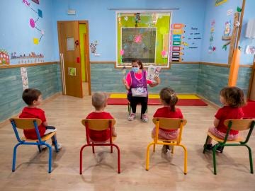 Una educadora de un centro de educación infantil les cuenta un cuento a varios niños y niñas en Murcia 