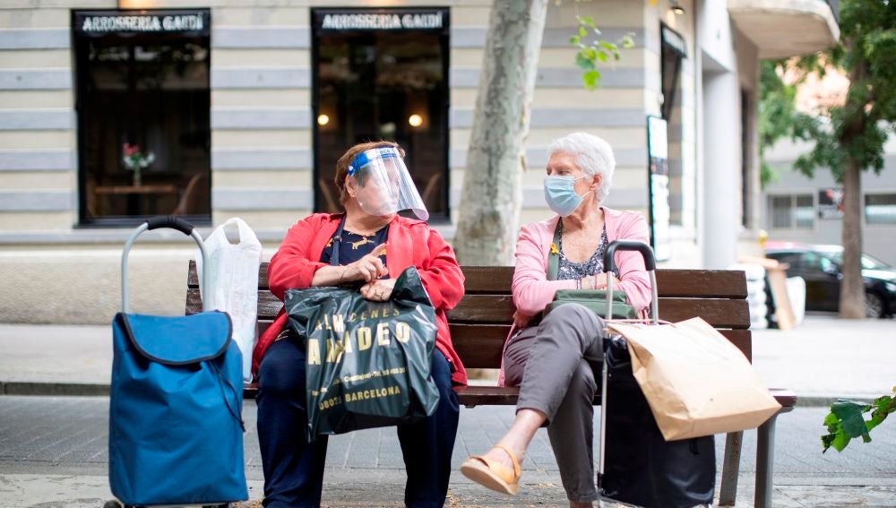 Dos señoras charlan sentadas en un banco del barcelonés barrio de la Sagrada Familia